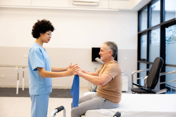 istock Physical therapist guiding a patient doing his exercises with a resistance band 2159759654