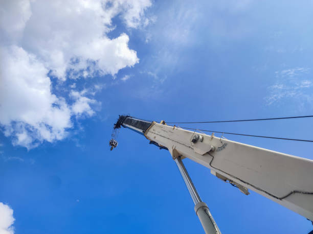 crane boom and hook ready for lifting against bright blue sky background