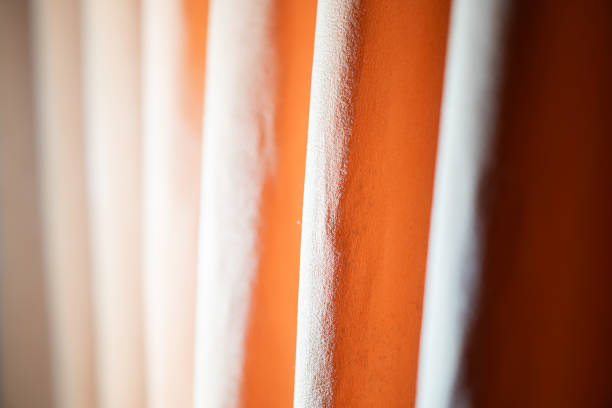 Close-up of beige and orange curtains with soft lighting creating shadows and texture.