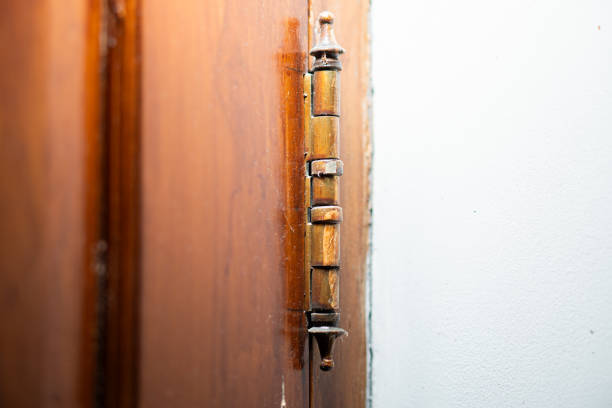 Close-up of an old brass door hinge attached to a wooden door frame.