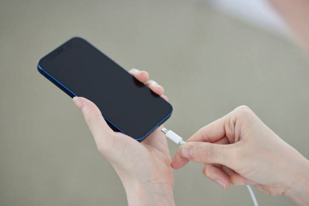 istock A Japanese woman's hand plugging a charger cord into a smartphone 2159768013