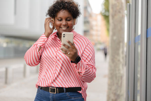 istock Woman Smiling While Using Smartphone and Headphones 2159768573