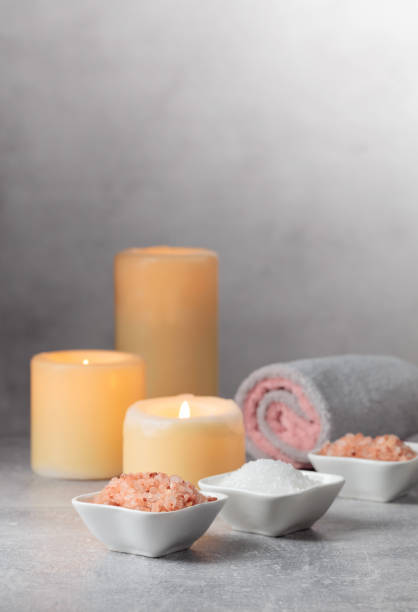 Sea salt, towels, and burning candles on a grey background. Spa concept with copy space.