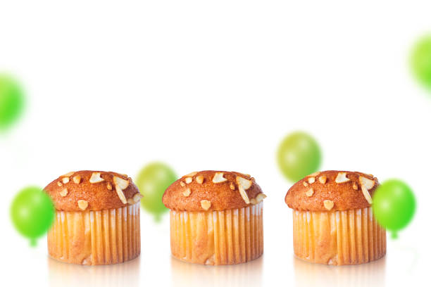 Muffins and green balloons on white background with space for text. Birthday Celebration background.