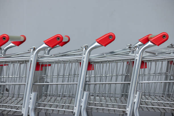 A row of shopping carts with red handles. The carts are lined up next to each other