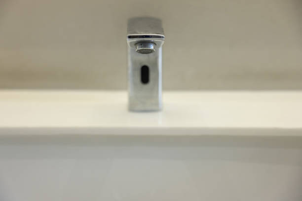 A silver faucet with a hole in the middle. The faucet is on a white countertop