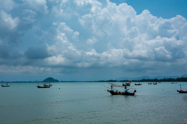 Fluffy clouds drift across a bright summer sky above a tropical beach with turquoise waves lapping at the shore