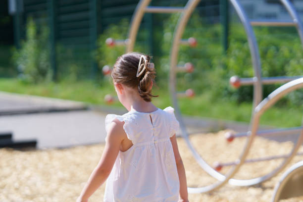A cute young girl, missing one tooth, having fun in the summer sun on the playground.