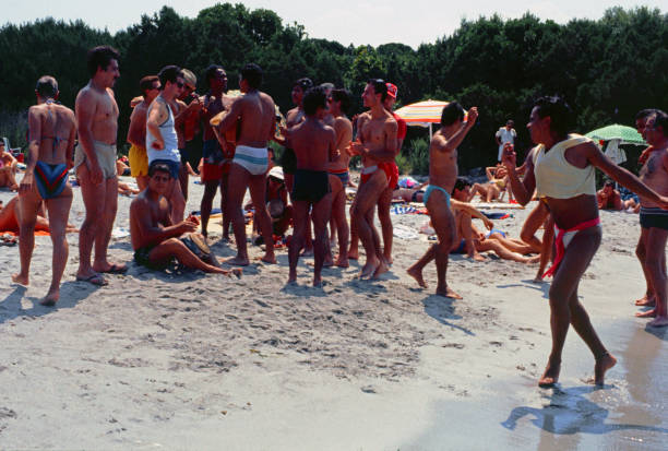 Sardina, Sardinia, Italy - 15 July 1986: on a splendid beach with soft golden sand some holidaymakers looking for fun prepare to dance to the rhythm of music.