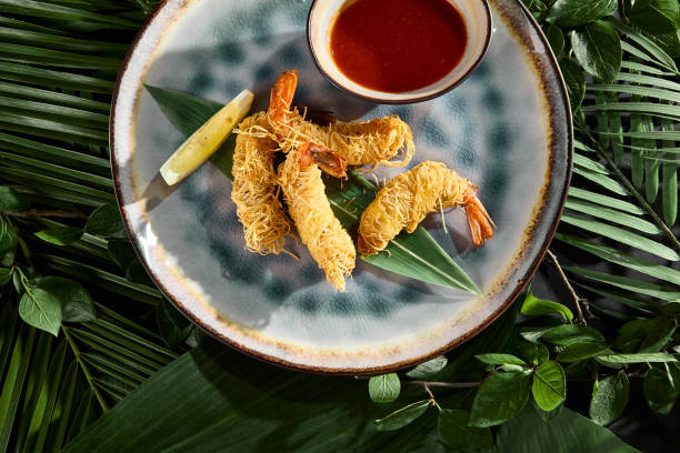 istock Shrimp in Kataifi Dough with Sauce on Tropical Leaves Background 2159783407