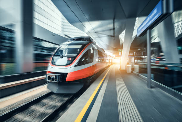 istock High-speed orange passenger train moving at railway station platform at sunset. Train station. Modern railway transportation concept with blurred motion effect. Railroad. Commercial transport 2159784118