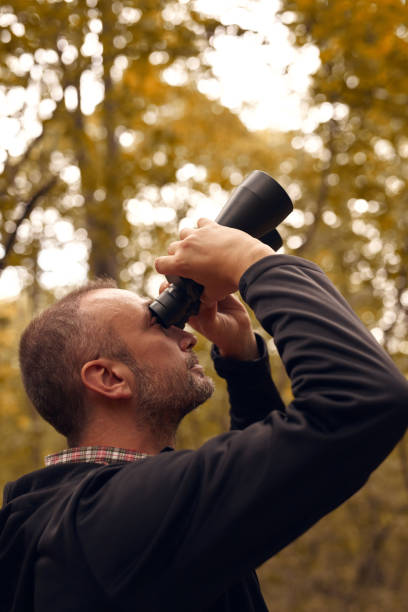 istock Man using binoculars for birdwatching and other observing animals in nature. 2159784146