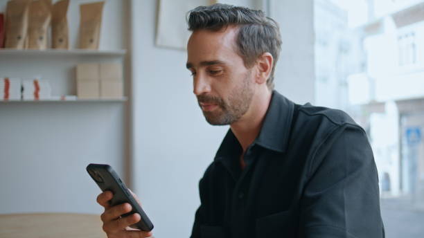 istock Handsome guy chatting cellphone social networks drinking coffee in cafe close up 2159787107
