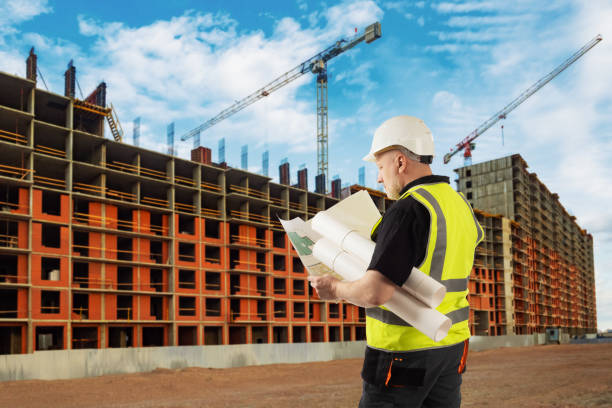 Urban construction. An architect at a construction site. Civil engineer with drawings. Foreman on the background of a house under construction. New multi-storey building. City architecture