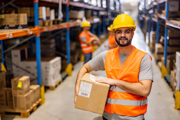 istock Portrait of smiling warehouse worker with box 2159806015