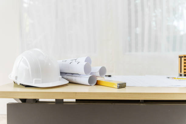 istock An architect's desk with blueprints and a white hardhat sits empty, ready for the next project. No people are present, highlighting the tools of the trade. 2159808523