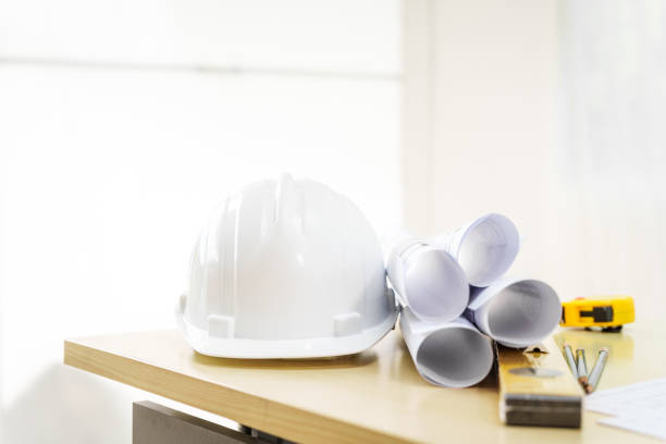 istock An architect's desk with blueprints and a white hardhat sits empty, ready for the next project. No people are present, highlighting the tools of the trade. 2159808524