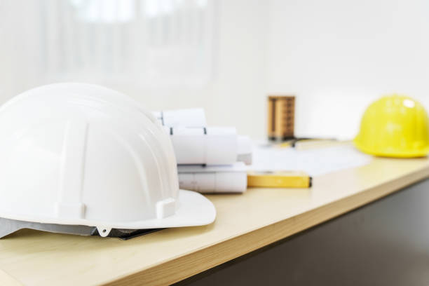 istock An architect's desk with blueprints and a white hardhat sits empty, ready for the next project. No people are present, highlighting the tools of the trade. 2159808533