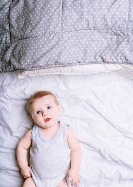 istock Cute baby boy lying on a white bed looking up 2159810425
