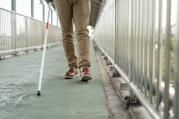istock Young blind man walking in city with walking stick. Visually impaired man difficult to traveling on the road wearing sun glasses Cross the road cross the footbridge 2159814711