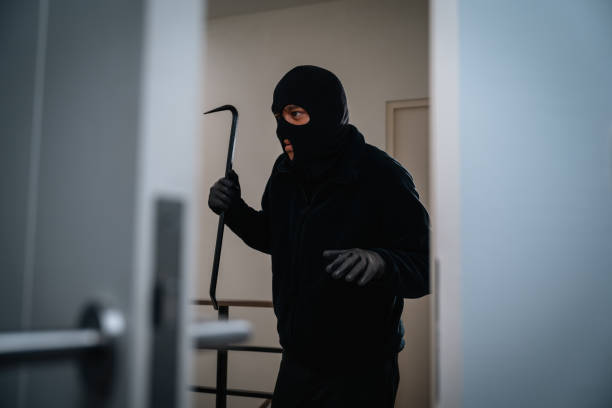 istock Thief in uniform black jacket various action housebreak. The Robber terrorism criminal escapes with balaclava and crowbar entering a house for stealing Housebreak at night 2159814979