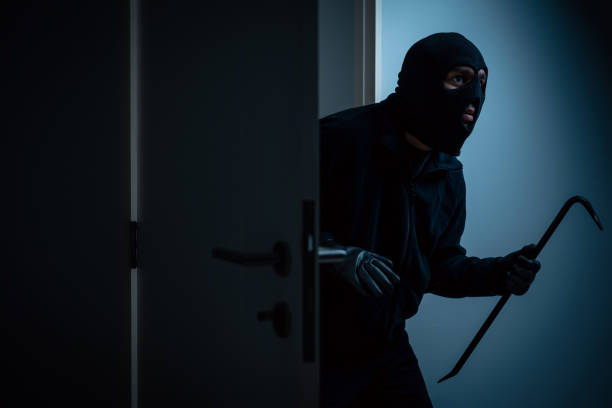 istock Thief in uniform black jacket various action housebreak. The Robber terrorism criminal escapes with balaclava and crowbar entering a house for stealing Housebreak at night 2159815802