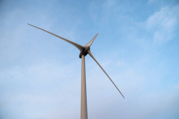 A close-up view of a wind turbine against a clear blue sky.