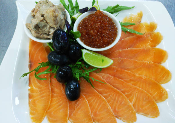 assorted fish: salmon, red caviar, cod liver, olives and lemon on a large plate