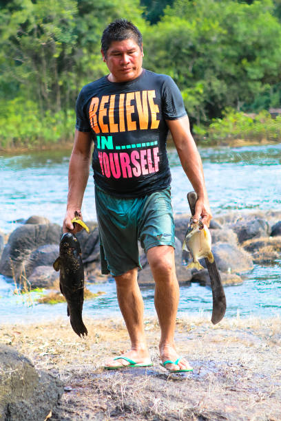 Kwamalasamutu, Suriname – November 25, 2016: An indigenous men shows his catch of fish, which he caught in a river in the tropical rainforest.
