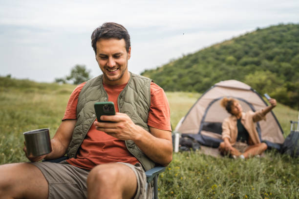istock Boyfriend use mobile phone on camp with girlfriend in the background 2159842843