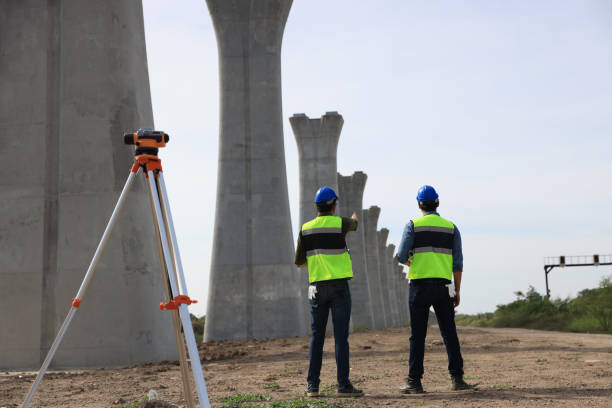 istock Survey construction technicians wearing safety vests and hard hats work with level survey cameras at road construction  site 2159842878