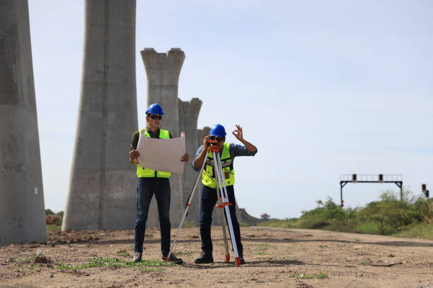 istock Two male  construction engineers  in safety vests and helmets discussing plans under the motorway  bridge at the construction site 2159842924