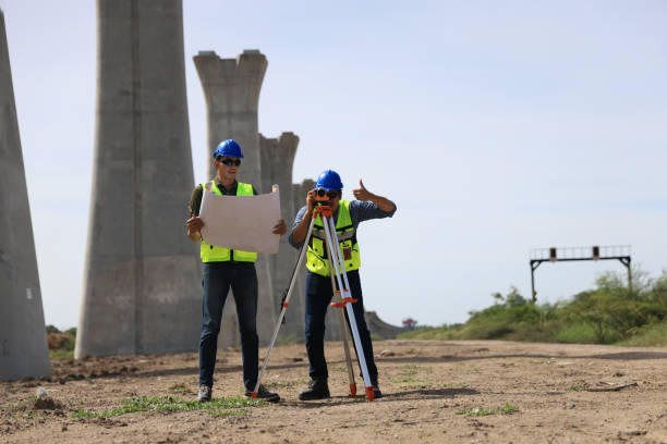 istock Two male  construction engineers  in safety vests and helmets discussing plans under the motorway  bridge at the construction site 2159842935
