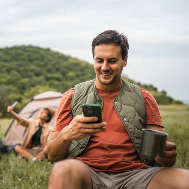 istock Boyfriend use mobile phone on camp with girlfriend in the background 2159843045