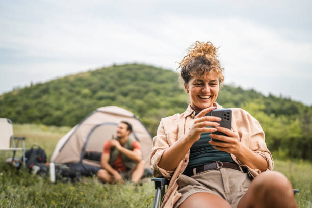 istock Girlfriend use mobile phone on camp with boyfriend in the background 2159843609