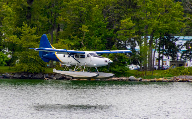 Seaplane in the air at low altitude about to land in the lake with Stanley Island Park in the background vancouver Canada