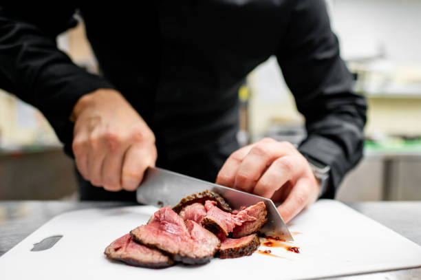 istock Close-up of hands slicing cooked steak on a white cutting board 2159848389