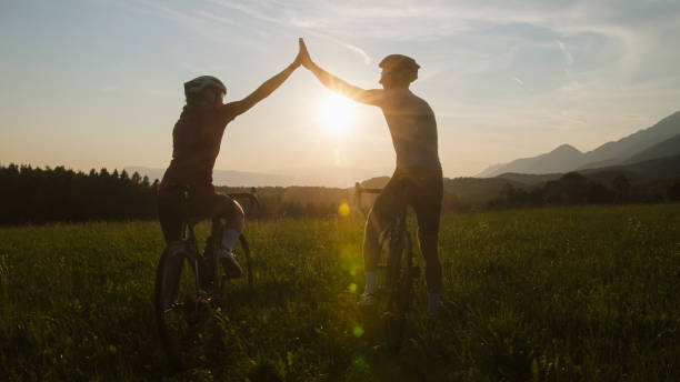 istock Two road cyclists on a glade with mountain view at sunset, aerial shot 2159855794