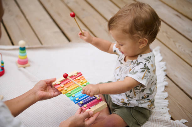 istock Baby playing xylophone with parent support outdoors 2159857964