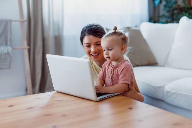 istock Mom and child seated on floor together using laptop. 2159860702