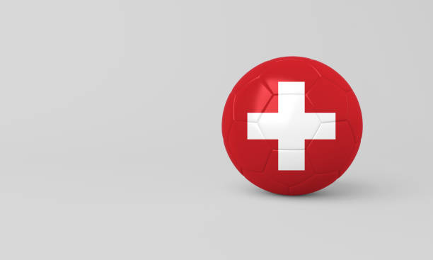 Close-up, detail view of an official diplomatic sign for a Swiss Consulate mounted on a dark grey wooden exterior wall. The sign features the national Coat of Arms of Switzerland, a prominent white Greek cross displayed on a red shield background, glossy and slightly convex. Above the central emblem, capital red letters spell \
