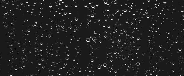istock Atmospheric minimal grayscale backdrop with rain droplets on glass. Wet window with rainy drops and dirt spots closeup. Blurry minimalist monochrome background of dirty window glass with raindrops. 2159868199