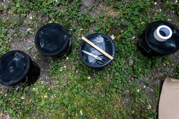 Stockholm, Sweden Black plastic cans with paint laying on the grass.with a wooden stirrer and masking tape.