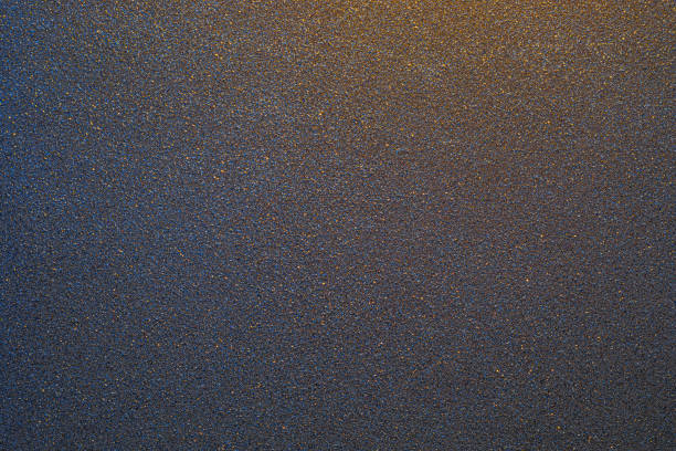A close-up view shows a black textured surface cast iron grill pan with small grains under bright light. The focus highlights the details and structure of the material seen during midday.