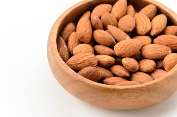 istock unglazed almonds in a Wooden round bowl on a white background 2159874270