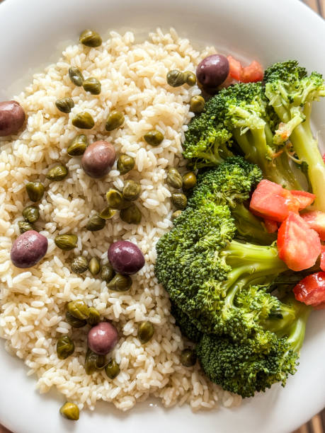 istock Plain rice with olives and capers and steamed broccoli and sliced tomatoes on side 2159877127