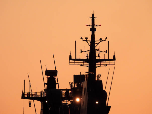The communications masts of HMAS Canberra, L-02, a Canberra Class amphibious assault ship of the Royal Australian Navy docked at Garden Island naval base in Sydney Harbour.  This image was taken from Woolloomooloo Bay on a cold and sunny morning at sunrise on 29 June 2024.