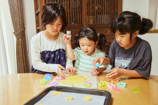 istock Sisters enjoying decorating cookies at home 2159891493