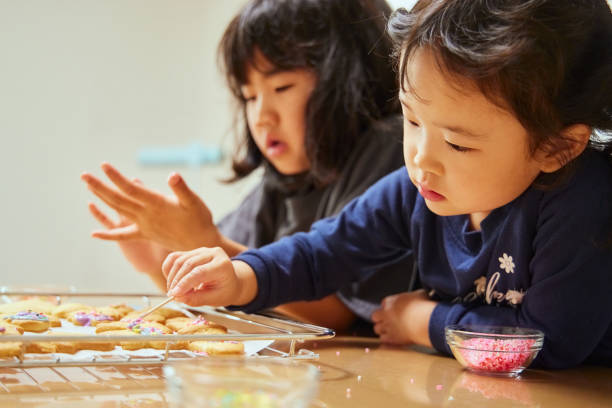 istock Sisters enjoying decorating cookies at home 2159891549