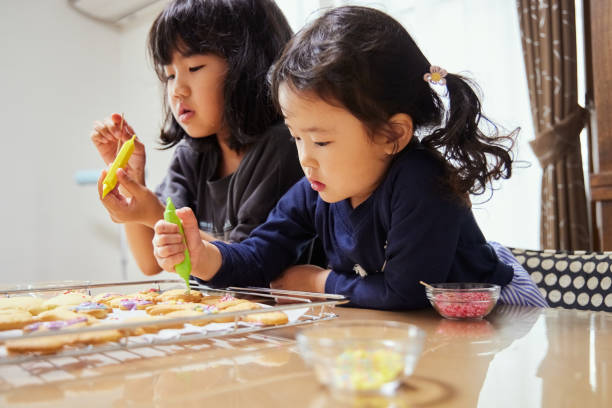 istock Sisters enjoying decorating cookies at home 2159891563